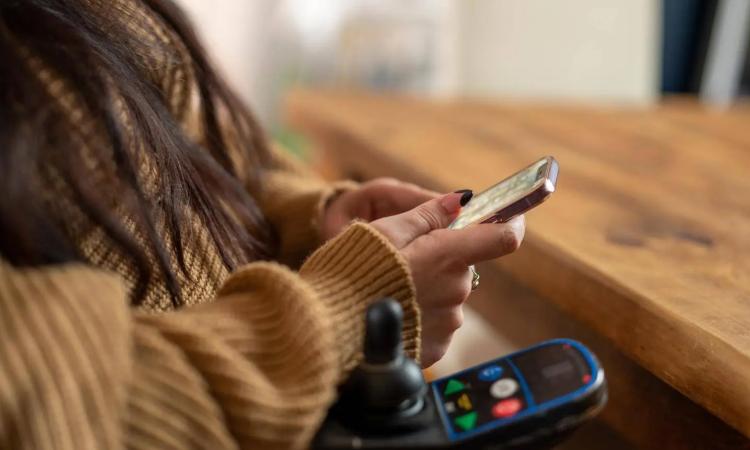 Photo of woman holding cellphone in wheelchair