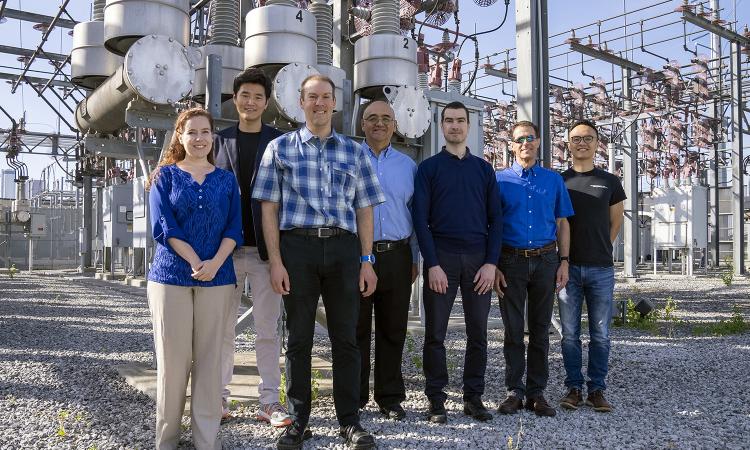 The TESLA (Tough and Ecological Supercritical Line Breaker for AC) team in front of high-voltage circuit breakers. 