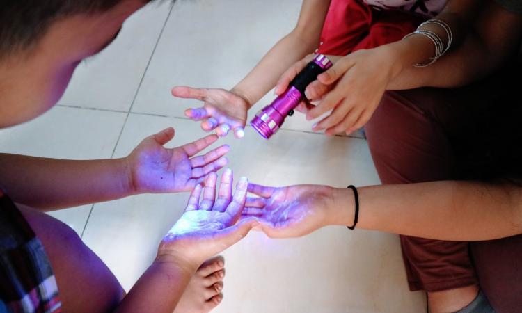 A black light shows "germs" on children's hands 