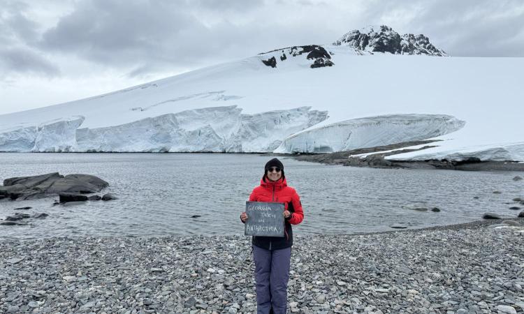 Ph.D. candidate Shweta Dutta in Horseshoe Island, Antarctica holding a Georgie Tech sign.
