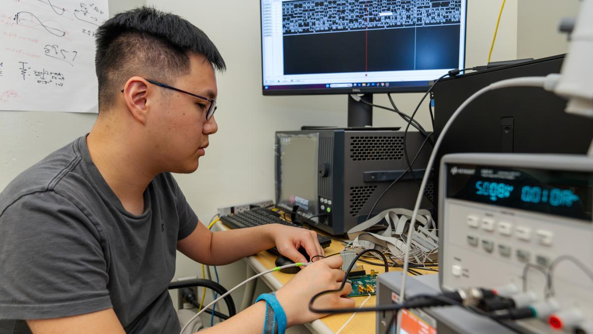 Student working on chip with computer in background