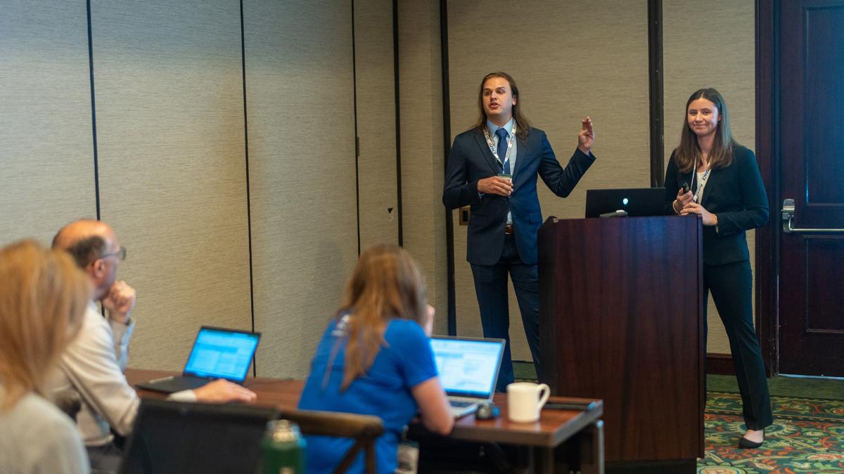 PCM Graduate and Undergraduate lead Kallen Cunningham and Rose Rye presenting to a panel of industry experts