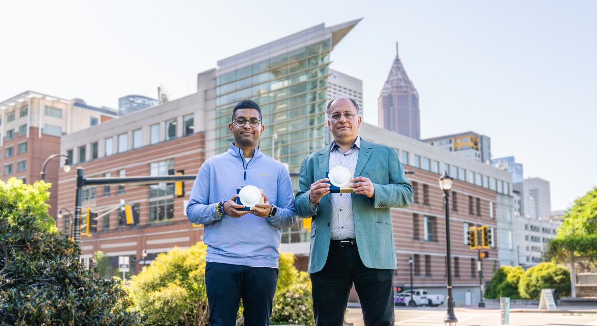 Marvin and Manos Holding Lens Device for Low Power Communication with the Atlanta mid-town skyline in the background. 