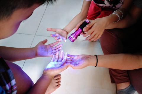 A black light shows "germs" on children's hands 