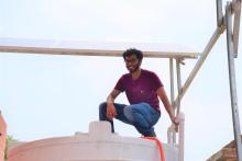 Duggal sits on the top of the filtered water tank under the solar panels that power the water purification facility during his internship at GRID.
